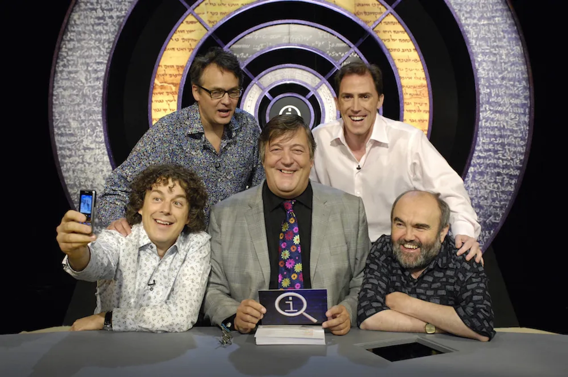 Stephen Fry, Rob Brydon, Alan Davies, Andy Hamilton, and Charlie Higson in QI (2003)